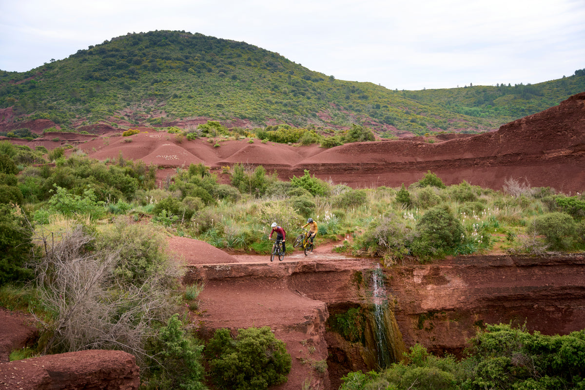 Two mountain bikers ride along an open dirt trail